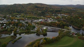 AX150_285 - 5.5K aerial stock footage flying over Ammonoosuc River, by rural town, Bath-Haverhill Bridge, autumn, Woodsville, New Hampshire
