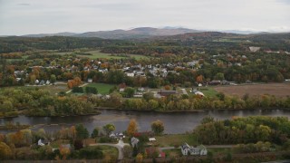 AX150_290 - 5.5K aerial stock footage flying by small rural town, Connecticut River, autumn, overcast, Woodsville, New Hampshire