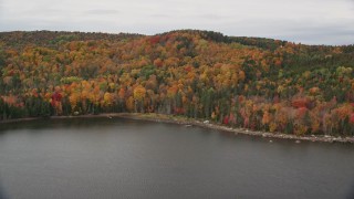 AX150_336E - 5.5K aerial stock footage approaching, flying over colorful forest, Thurman W Dix Reservoir, autumn, Orange, Vermont, reveal Barre