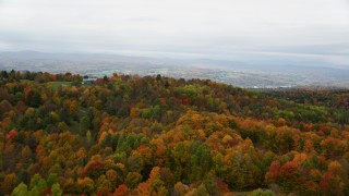 AX150_339 - 5.5K aerial stock footage flying over colorful forest, reveal rural homes, overcast, autumn, Barre, Vermont