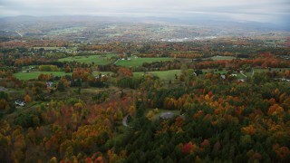 AX150_340 - 5.5K aerial stock footage flying over rural homes, colorful foliage, autumn, overcast, Barre, Vermont