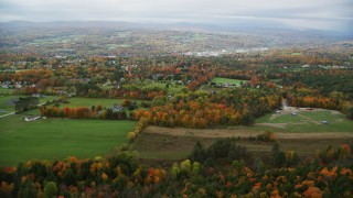 AX150_341 - 5.5K aerial stock footage flying over rural homes, grassy clearings, trees in autumn, overcast, Barre, Vermont