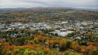 AX150_345 - 5.5K aerial stock footage flying by homes, colorful autumn foliage, downtown, Barre, Vermont
