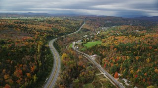 AX150_346 - 5.5K aerial stock footage flying over Route 62,  Main Street near rural homes, colorful forest in autumn, Barre, Vermont