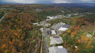 AX150_348 - 5.5K stock footage aerial video flying by strip malls, Main Street, colorful foliage in autumn, Barre, Vermont