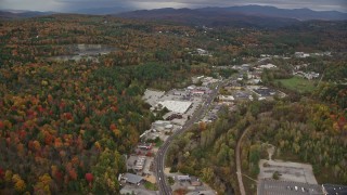 AX150_348E - 5.5K aerial stock footage flying by strip malls, Main Street, colorful foliage in autumn, Barre, Vermont