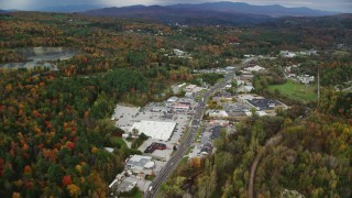 AX150_349 - 5.5K stock footage aerial video flying over colorful trees, strip malls on Main Street in autumn, Barre, Vermont