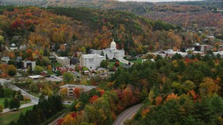 AX150_384 - 5.5K aerial stock footage flying away from Vermont State House, by colorful trees, autumn, Montpelier, Vermont
