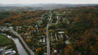 AX150_392 - 5.5K aerial stock footage flying by neighborhood near river, colorful trees in autumn, Montpelier, Vermont