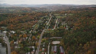 AX150_392E - 5.5K aerial stock footage flying by neighborhood near river, colorful trees in autumn, Montpelier, Vermont