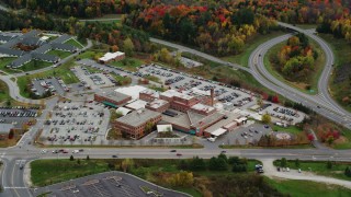 AX150_397 - 5.5K aerial stock footage flying by Central Vermont Medical Center, roads, foliage in autumn, Barre, Vermont