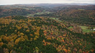 AX150_413E - 5.5K aerial stock footage flying over colorful forest, farmland, autumn, overcast, Randolph Center, Vermont