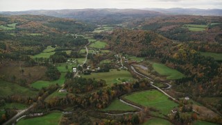 AX150_417E - 5.5K aerial stock footage flying over Route 14, farms, rural homes and small town, autumn, Bethel, Vermont