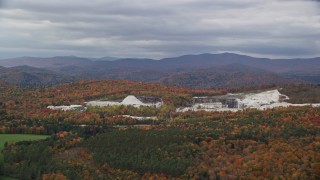 AX150_419E - 5.5K aerial stock footage flying by a colorful forest, quarry, autumn, overcast, Bethel, Vermont