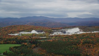 AX150_420 - 5.5K aerial stock footage flying by brightly colored forest, quarry, autumn, overcast, Bethel, Vermont