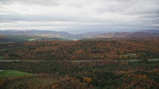 AX150_421E - 5.5K aerial stock footage flying by colorful forests and hills in autumn, overcast sky, Bethel, Vermont