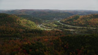 AX150_425 - 5.5K stock footage aerial video flying over colorful forest, hills, approach small farms, autumn, South Royalton, Vermont