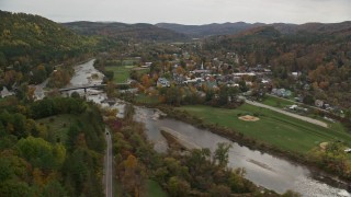 AX150_428E - 5.5K aerial stock footage flying by small bridge, White River, small rural town, autumn, South Royalton, Vermont