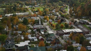 AX150_434 - 5.5K stock footage aerial video orbiting homes, churches and town square in small rural town, autumn, South Royalton, Vermont