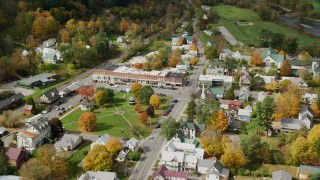 AX150_437 - 5.5K aerial stock footage orbiting town square, row of shops, colorful foliage in small town, autumn, South Royalton, Vermont