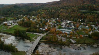 AX150_441 - 5.5K stock footage aerial video flying over small bridge, White River, approach churches, small town, autumn, South Royalton, Vermont