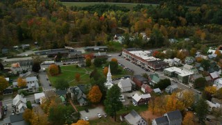 AX150_442 - 5.5K stock footage aerial video orbiting colorful foliage throughout small rural town adjacent to the town square, autumn, South Royalton, Vermont