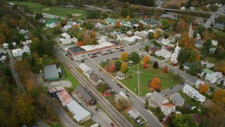 AX150_443 - 5.5K stock footage aerial video orbiting small rural town in autumn, town square, shops, churches, South Royalton, Vermont