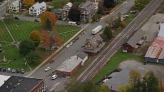 AX150_444E - 5.5K aerial stock footage orbiting railroad tracks and station, small rural town, autumn, South Royalton, Vermont