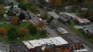 AX150_445 - 5.5K stock footage aerial video orbiting railroad tracks and station, town square, small town, autumn, South Royalton, Vermont