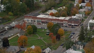 AX150_447E - 5.5K aerial stock footage orbiting a row of shops near town square, small rural town, autumn, South Royalton, Vermont