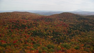 AX150_461E - 5.5K aerial stock footage flying over colorful, densely forested hills in autumn, North Pomfret, Vermont