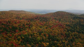 AX150_462 - 5.5K stock footage aerial video flying over brightly colored, forested hills, autumn, North Pomfret, Vermont