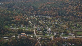 AX150_468E - 5.5K aerial stock footage flying by a small rural town, colorful foliage, autumn, cloudy, Quechee, Vermont