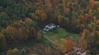 AX150_471 - 5.5K aerial stock footage flying by rural homes, lawns, brightly colored trees in autumn, Quechee, Vermont