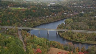 AX150_474E - 5.5K aerial stock footage flying by Interstate 89, small bridge, Connecticut River, autumn, Lebanon, New Hampshire