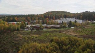 AX150_476 - 5.5K aerial stock footage flying by office buildings, colorful foliage, cloudy skies, autumn, Lebanon, New Hampshire