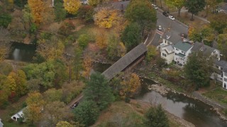AX151_020E - 5.5K aerial stock footage orbiting a small covered bridge, Ottauquechee River, autumn, Woodstock, Vermont
