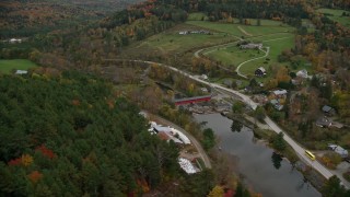 AX151_025E - 5.5K aerial stock footage flying over colorful forest, approach farms, small rural town, autumn, Taftsville, Vermont