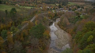 AX151_028E - 5.5K aerial stock footage approaching small covered bridge across Ottauquechee River, autumn, Taftsville, Vermont