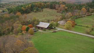 AX151_033 - 5.5K aerial stock footage orbiting small farm, barn, grass clearings, colorful foliage in autumn, Taftsville, Vermont