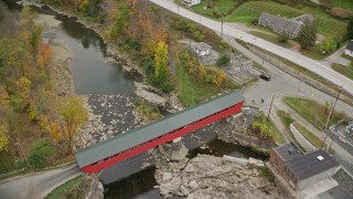 AX151_035E - 5.5K aerial stock footage approaching small rural town, reveal covered bridge, Ottauqueche River, autumn, Taftsville, Vermont