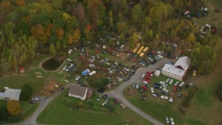 AX151_040E - 5.5K aerial stock footage flying by rural homes, colorful trees, tilt down over car junkyard, autumn, Hartland, Vermont