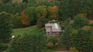 AX151_051E - 5.5K aerial stock footage flying by colorful trees, revealing isolated mansion, autumn, Cornish, New Hampshire