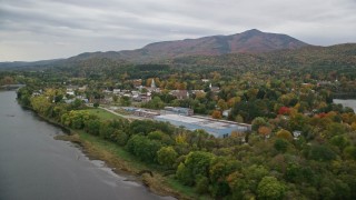 AX151_055E - 5.5K aerial stock footage flying over Connecticut River, approaching small town, autumn, Windsor, Vermont