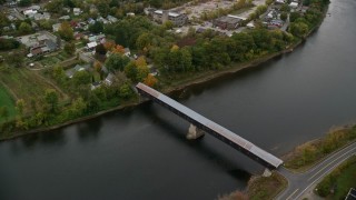 AX151_058E - 5.5K aerial stock footage flying by covered bridge, Connecticut River, colorful trees, autumn, Windsor, Vermont