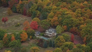 AX151_068 - 5.5K aerial stock footage flying away from isolated homes, brightly colored trees, autumn, Cornish, New Hampshire