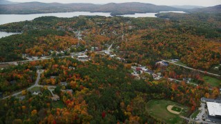 AX151_079 - 5.5K stock footage aerial video flying over colorful trees, small rural town, tilt down, autumn, Sunapee, New Hampshire