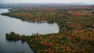 AX151_085 - 5.5K aerial stock footage flying by waterfront homes, colorful forest, Lake Sunapee, autumn, Newbury, New Hampshire