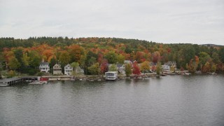 AX151_088E - 5.5K aerial stock footage orbiting colorful forest, waterfront homes, Lake Sunapee, autumn, Newbury, New Hampshire