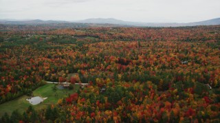 AX151_094 - 5.5K aerial stock footage flying over rural homes, brightly colored forest, autumn, Newbury, New Hampshire